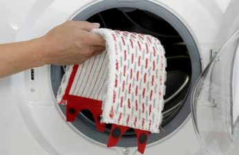primo piano della mano che mette il tampone in mircrofibra nella lavatrice